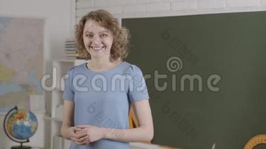 现代魅力教师。教师节。微笑的老师站在黑板前。回到学校。
